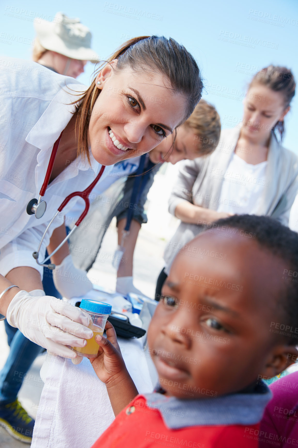 Buy stock photo Shot of a volunteer doctor giving checkups to underprivileged kids