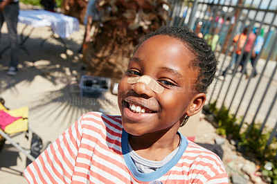Buy stock photo Shot of a little gilr with a plaster on her nose at a community outreach event