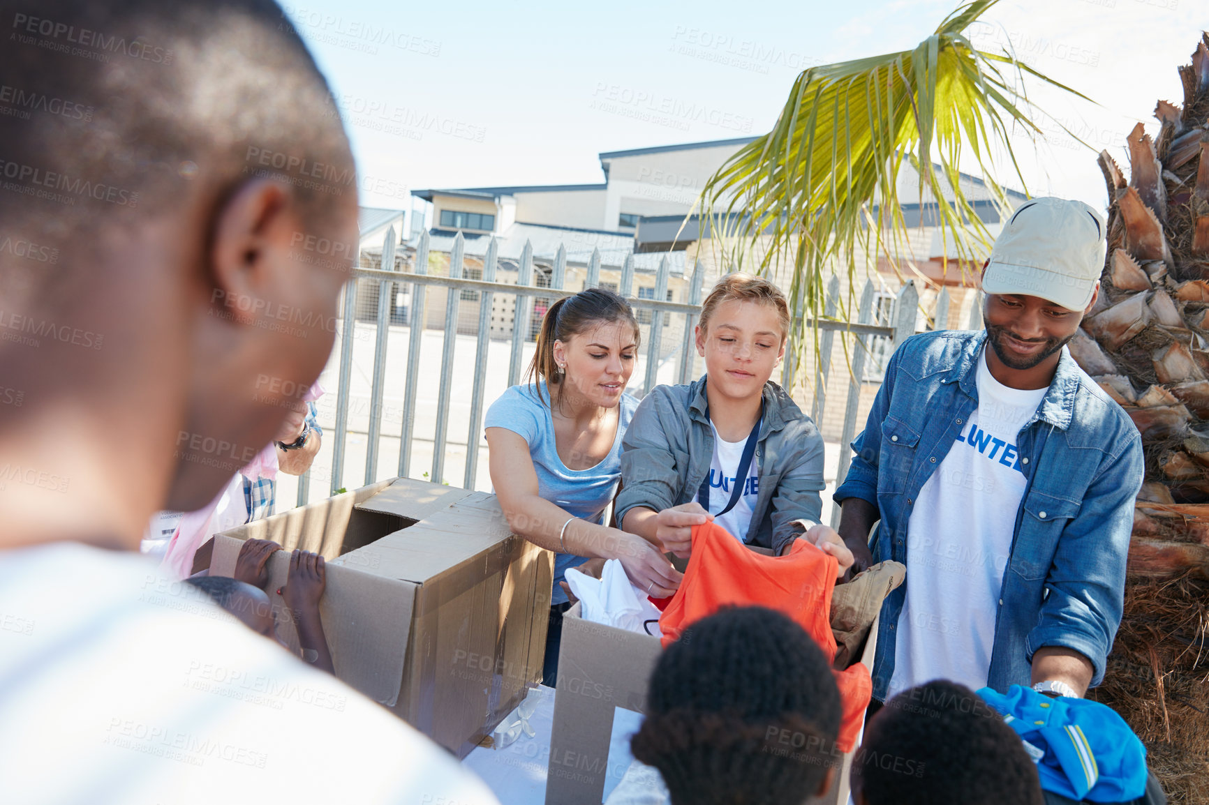 Buy stock photo Cropped shot of volunteer workers handing out clothing to underprivileged children 