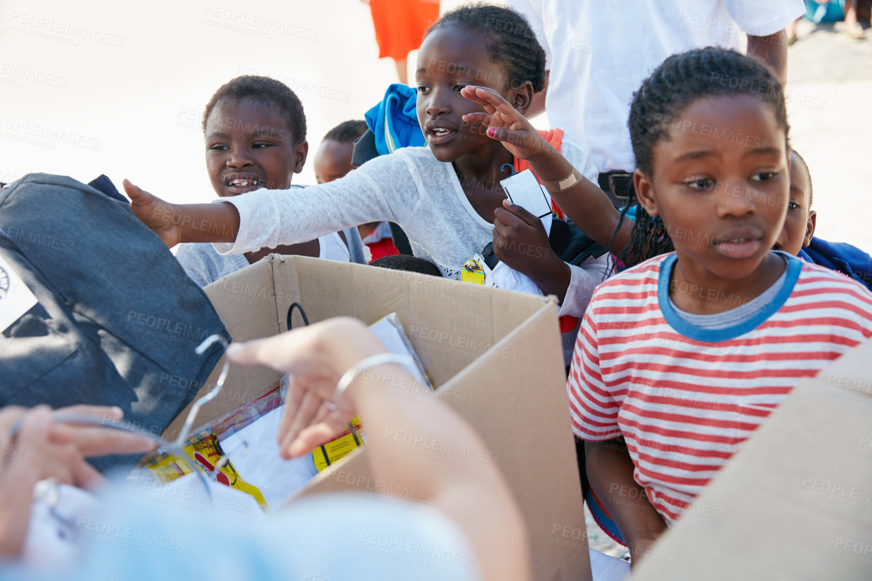 Buy stock photo Cropped shot of volunteer workers handing out clothing to underprivileged children 