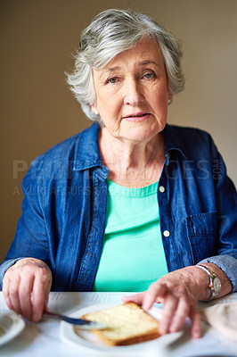 Buy stock photo Portrait of a senior woman buttering toast for breakfast