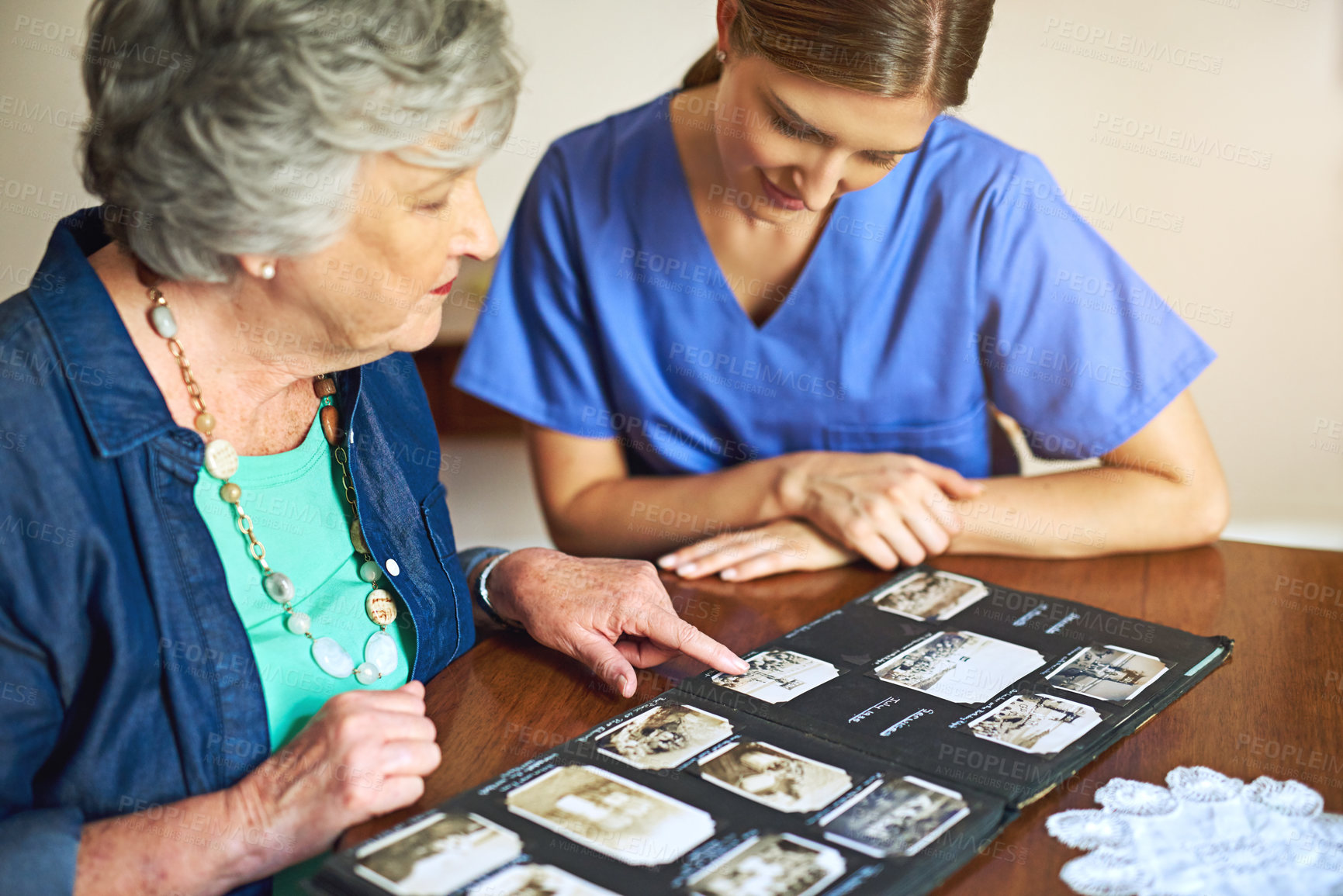 Buy stock photo Shot of a resident and a nurse looking through a photo album