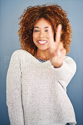 Buy stock photo Studio shot of a young woman showing the peace gesture against a grey background