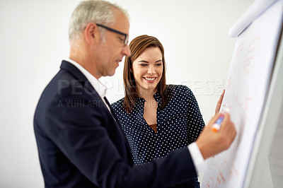 Buy stock photo Cropped shot of a mature businessman working on a whiteboard while a female colleague looks on