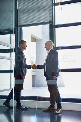 Buy stock photo Full length shot of two businessmen shaking hands in the lobby