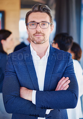 Buy stock photo Cropped portrait of a businessman standing in the office with his colleagues in the background