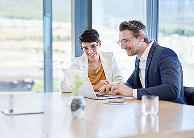 Buy stock photo Shot of two colleagues working on a laptop at a desk in an office