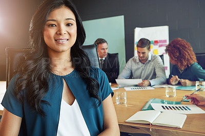 Buy stock photo Portrait of a businesswoman sitting in a meeting with her colleagues blurred in the background