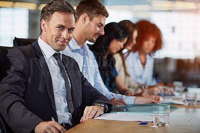 Buy stock photo Portrait of a businessman in a meeting with his colleagues in the background