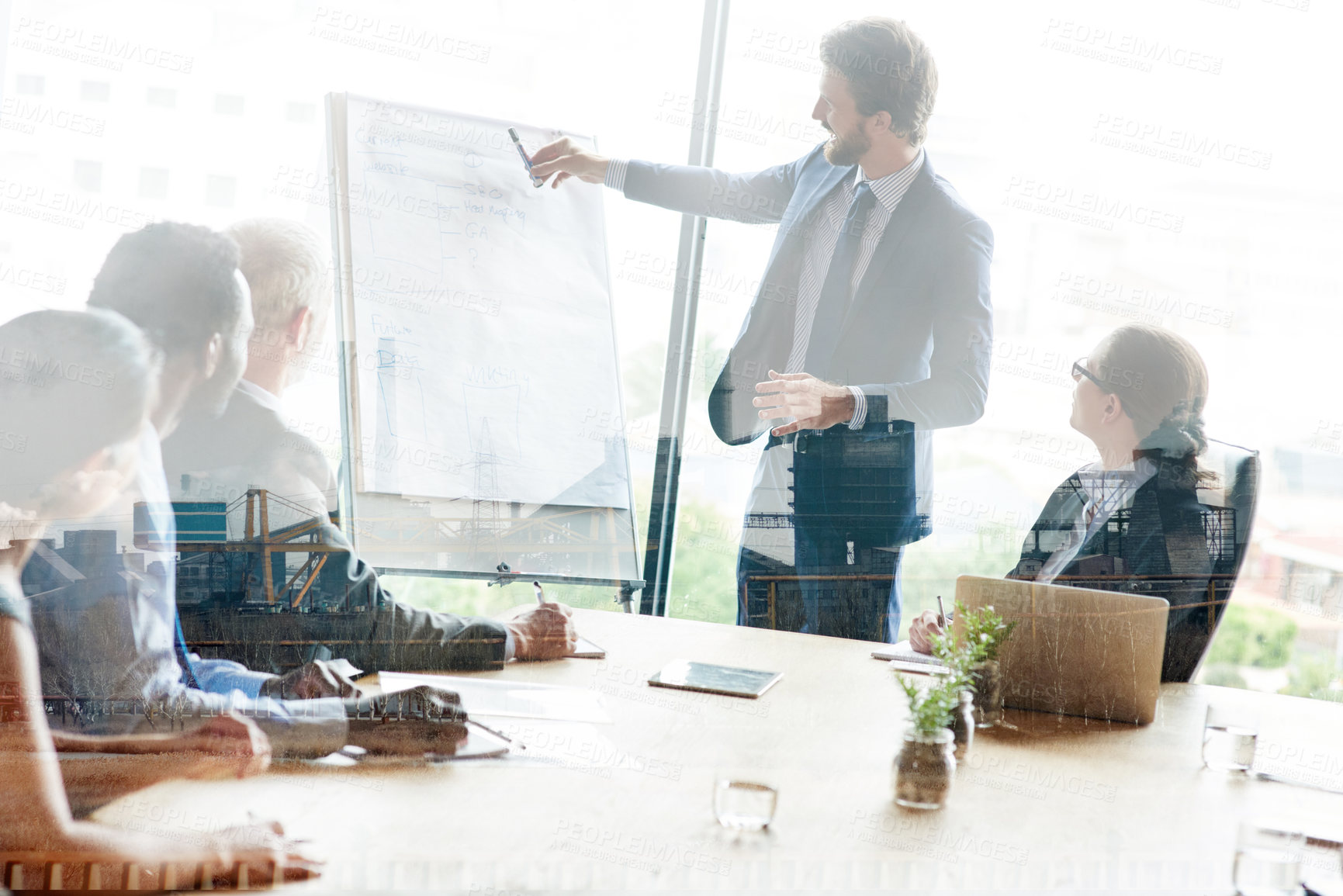 Buy stock photo Multiple exposure shot of colleagues in a presentation superimposed over an industrial background