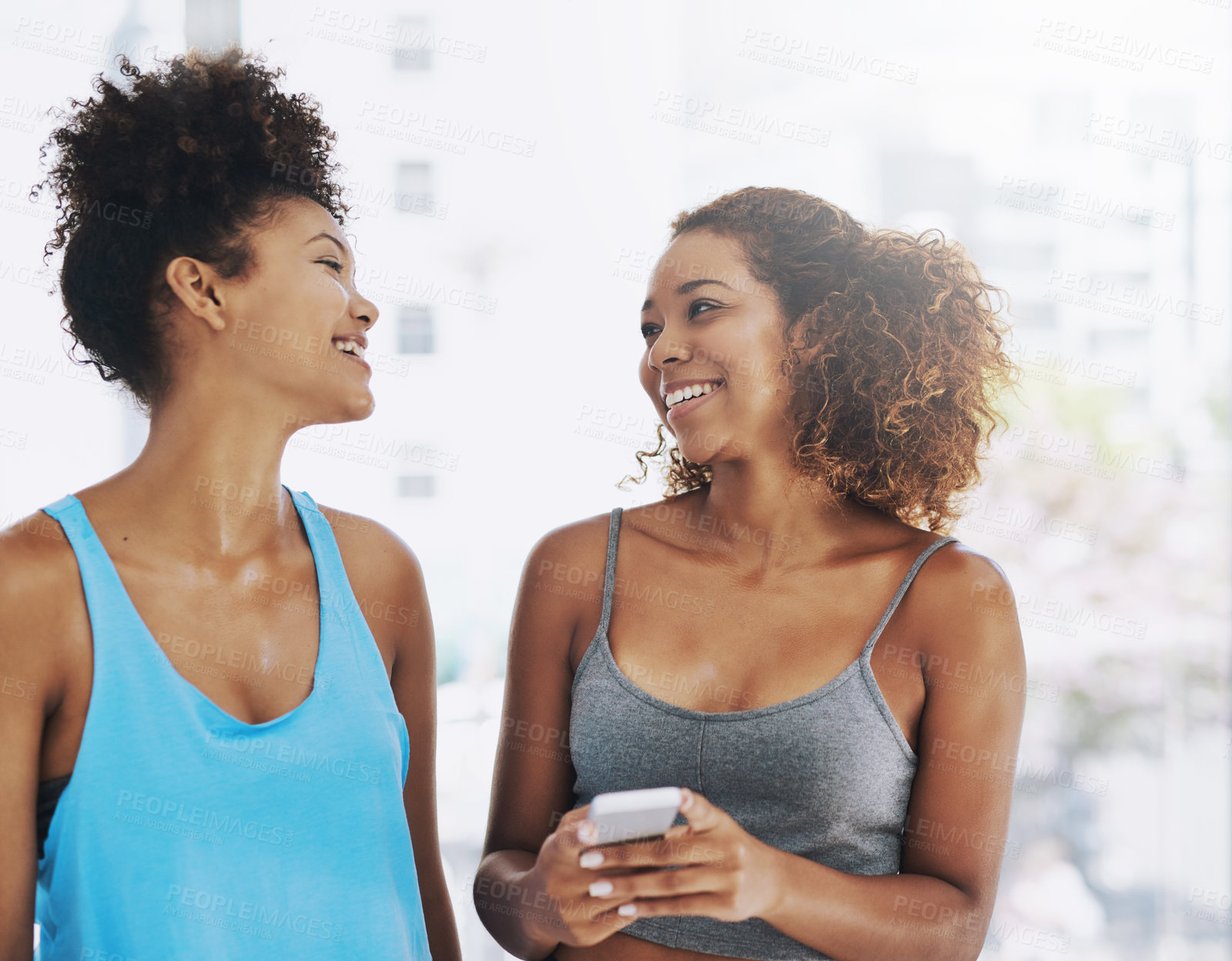 Buy stock photo Laughing, mobile and women on yoga class break for support, wellness or share health advice. Relax, phone or happy friends on floor talking in discussion or gossip together for news, rest or pilates