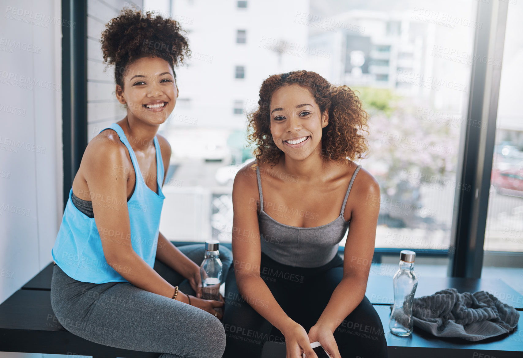 Buy stock photo Cropped portrait of two young women sitting on a bench after yoga class