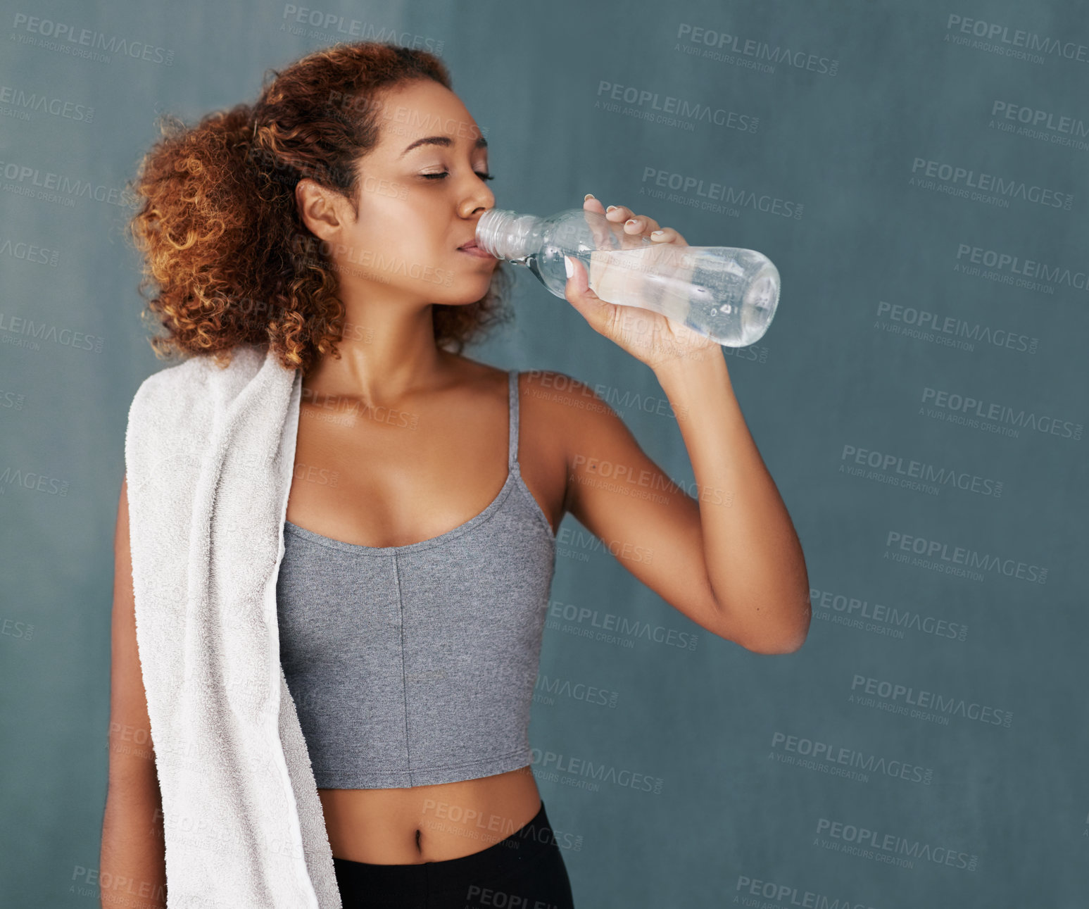 Buy stock photo Woman, thirsty and drinking water in studio after fitness, daily workout and exercise break for wellness. Female model, hydration and nutrition with h2o bottle for minerals, detox and gray background