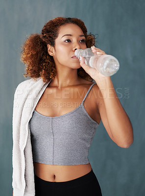 Buy stock photo Studio shot of a young woman drinking some water after yoga class against a grey background