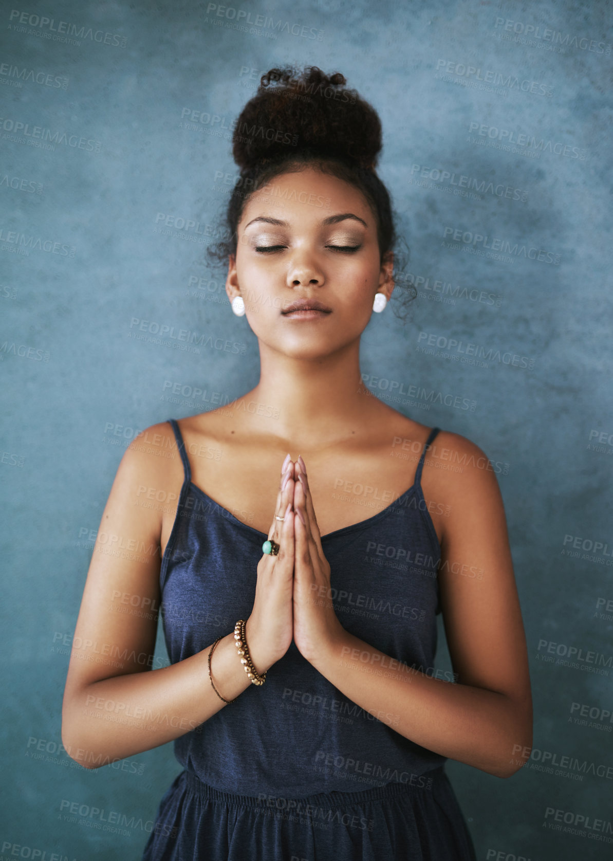 Buy stock photo Cropped shot of a young woman meditating against a grey background