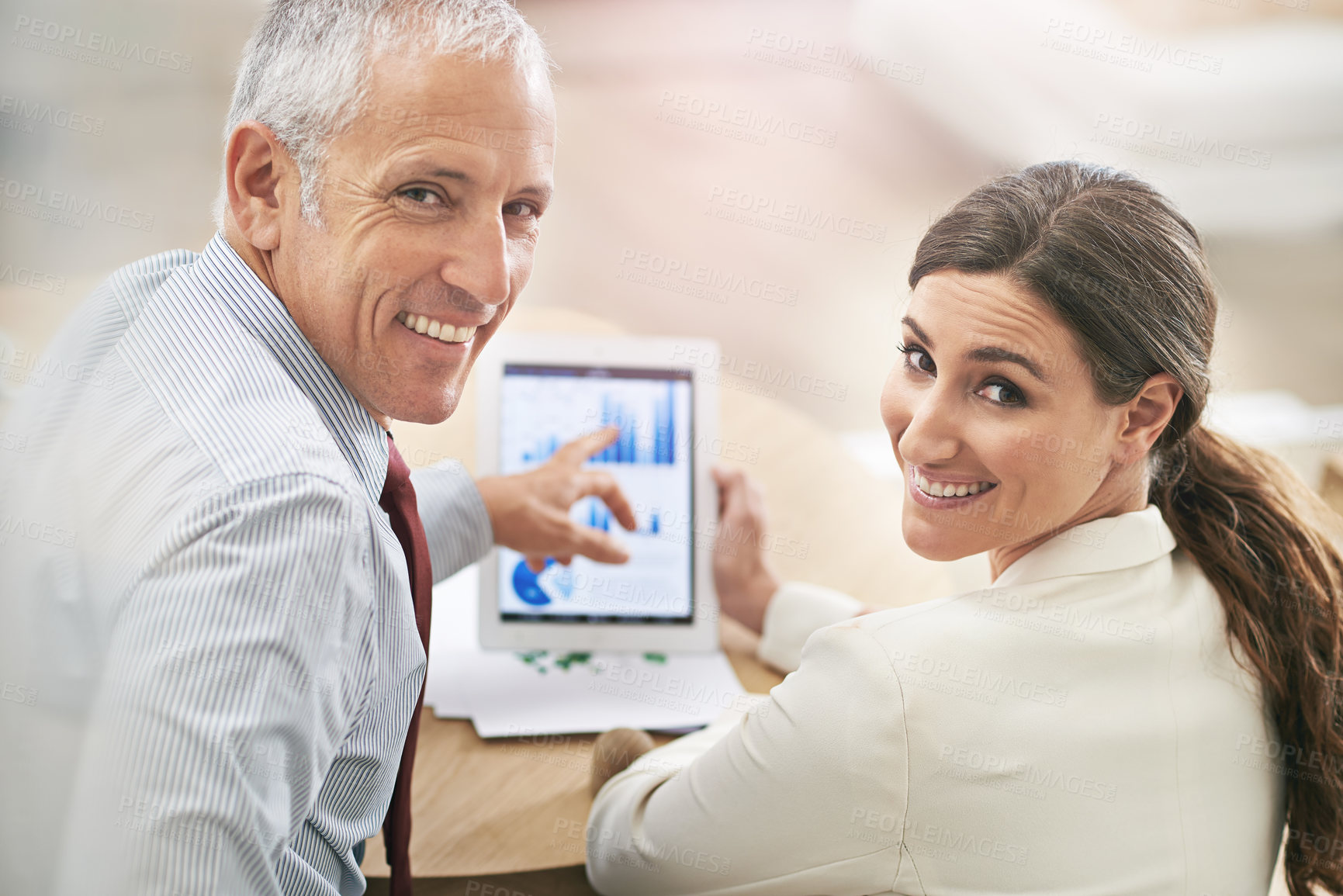 Buy stock photo Portrait of two coworkers sitting at a table using a digital tablet