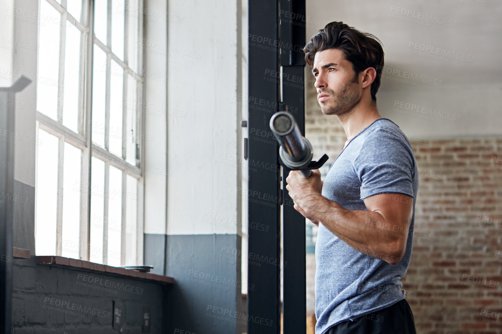 Buy stock photo Shot of a young man about to work out with weights in the gym