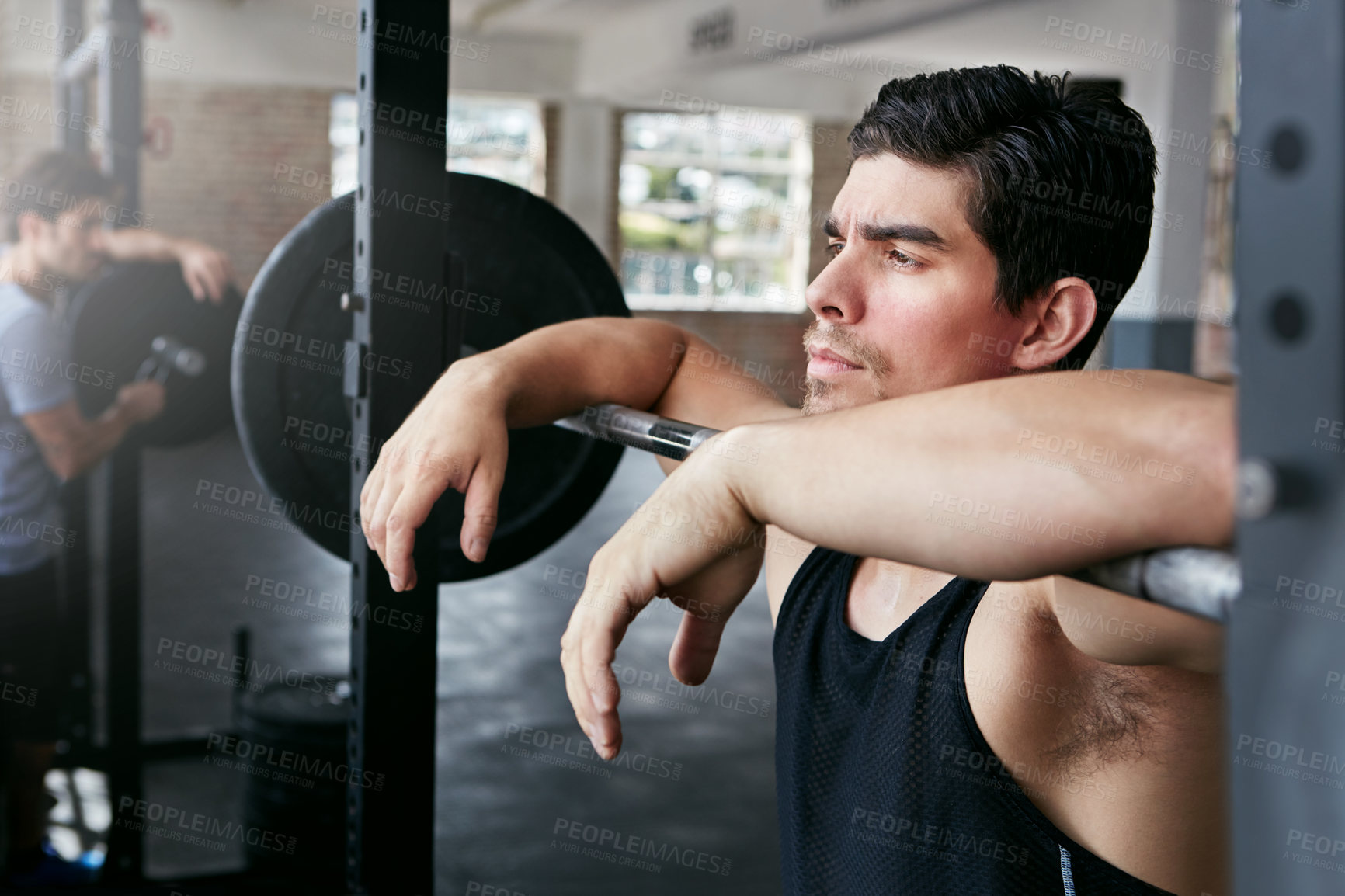 Buy stock photo Shot of a young man taking a break from working out with weights in the gym