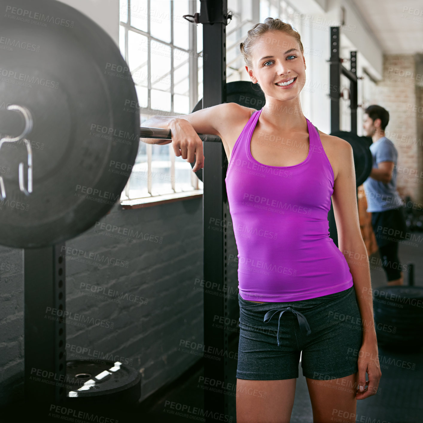 Buy stock photo Shot of a sporty young woman leaning on a barbell at the gym