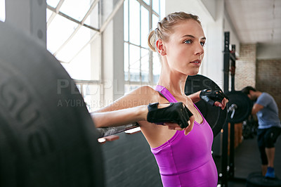 Buy stock photo Shot of a sporty young woman leaning on a barbell at the gym