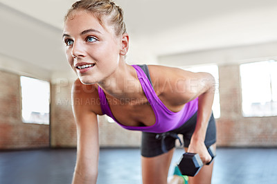 Buy stock photo Shot of a young woman working out with weights at the gym