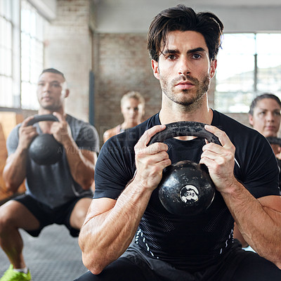 Buy stock photo Shot of a group of people doing squats with a kettle bell in a gym