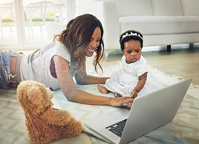 Buy stock photo Shot of a mother using a laptop with and her baby daughter at home