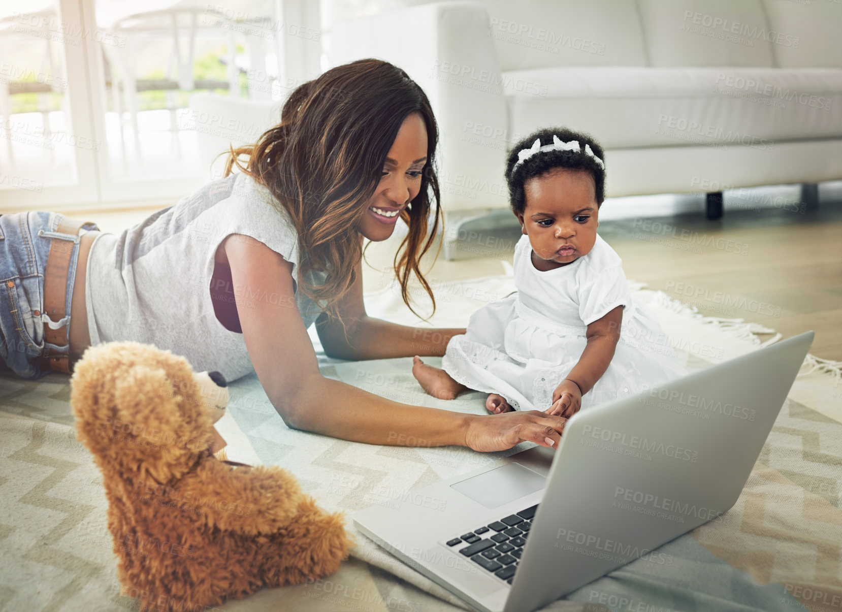 Buy stock photo Shot of a mother using a laptop with and her baby daughter at home