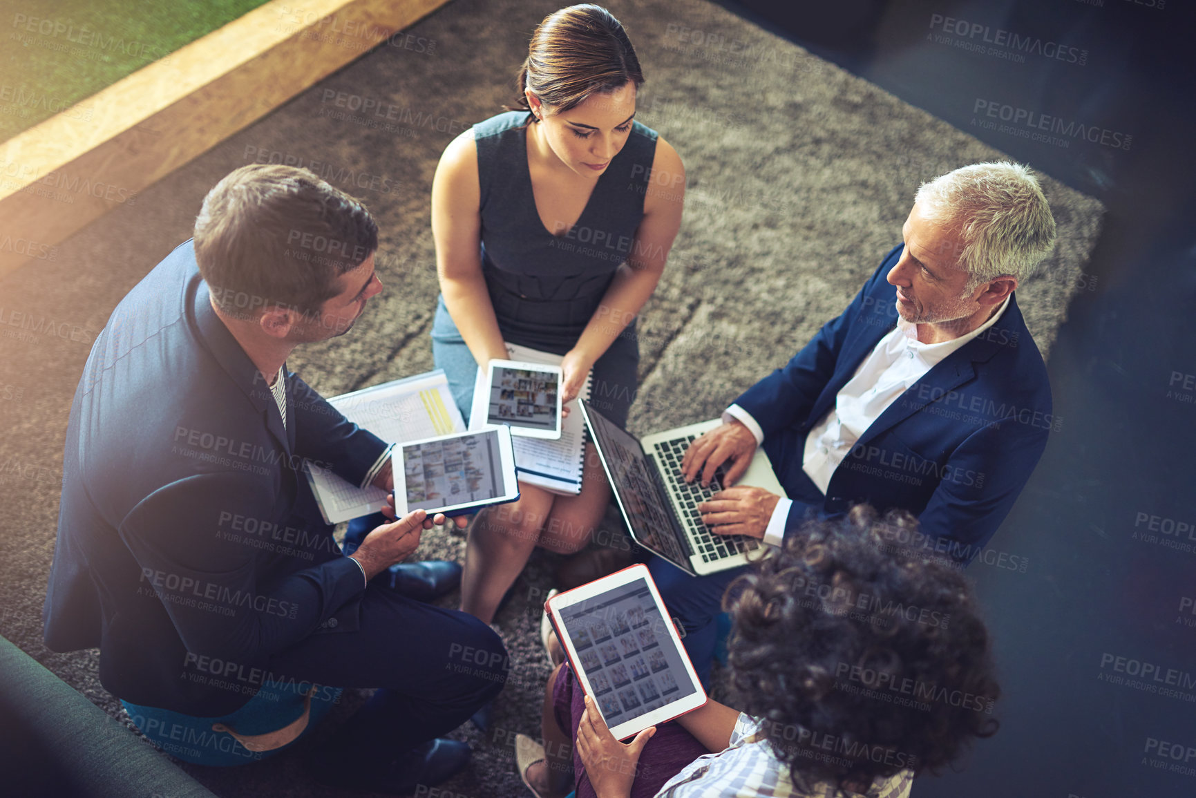 Buy stock photo High angle shot of a group of businesspeople using their digital tablets