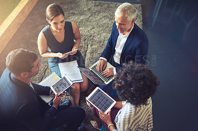 Buy stock photo High angle shot of a group of businesspeople using their digital tablets