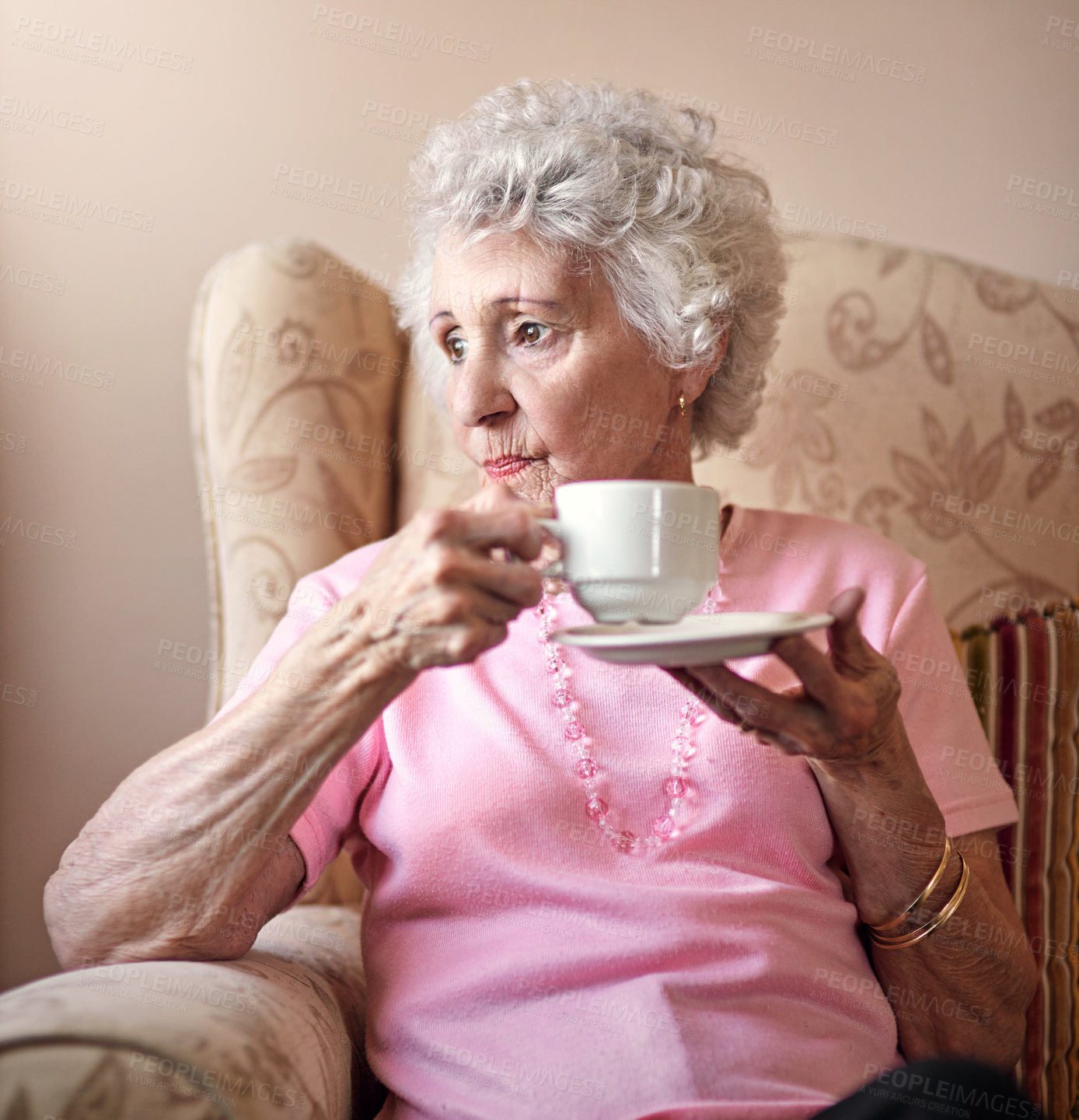 Buy stock photo Thinking, coffee and senior woman in armchair with history, nostalgia and comfort in nursing home. Relax, remember and elderly person on sofa in lounge with memory, tea and reflection in retirement.