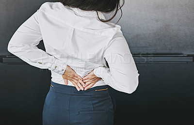 Buy stock photo Cropped shot of a businesswoman holding her lower back in discomfort