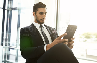 Buy stock photo Shot of a businessman using his tablet while sitting in an office