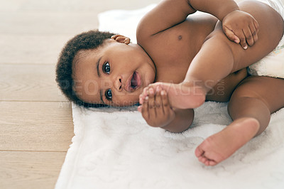 Buy stock photo Baby, infant and black child lying down newborn relax in a home, nursery or house floor with a diaper playing with feet. Cute, adorable and innocent little kid with happiness in development