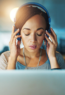 Buy stock photo Cropped shot of a young woman listening to music while working late in her office
