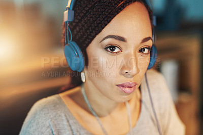 Buy stock photo Cropped portrait of a young woman listening to music while working late in her office