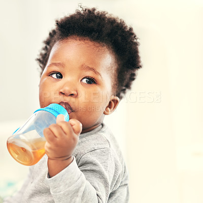 Buy stock photo Shot of a little baby boy drinking froma sippy cup at home