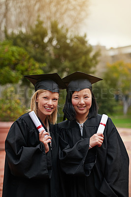 Buy stock photo Shot of two college graduates holding their diplomas