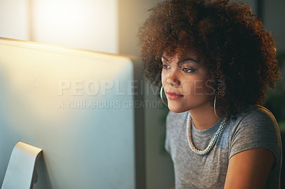 Buy stock photo Shot of a young woman using a computer during a late shift at the office