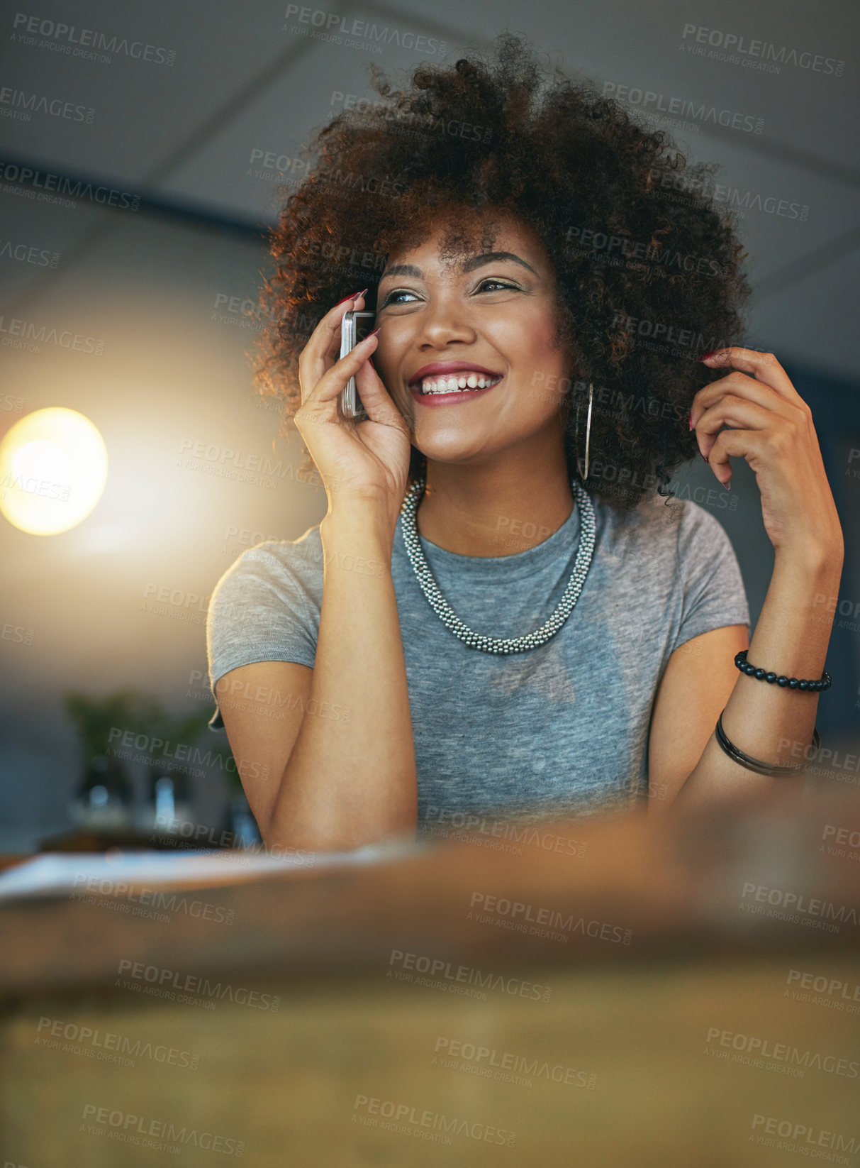 Buy stock photo Shot of a young woman talking on the phone during a late shift at the office