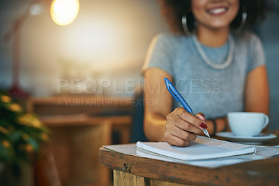 Buy stock photo Cropped shot of a woman writing in a notebook during a late shift at the office