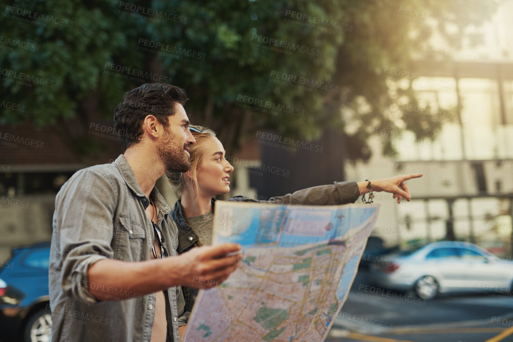 Buy stock photo Shot of a young couple using a map while exploring the city