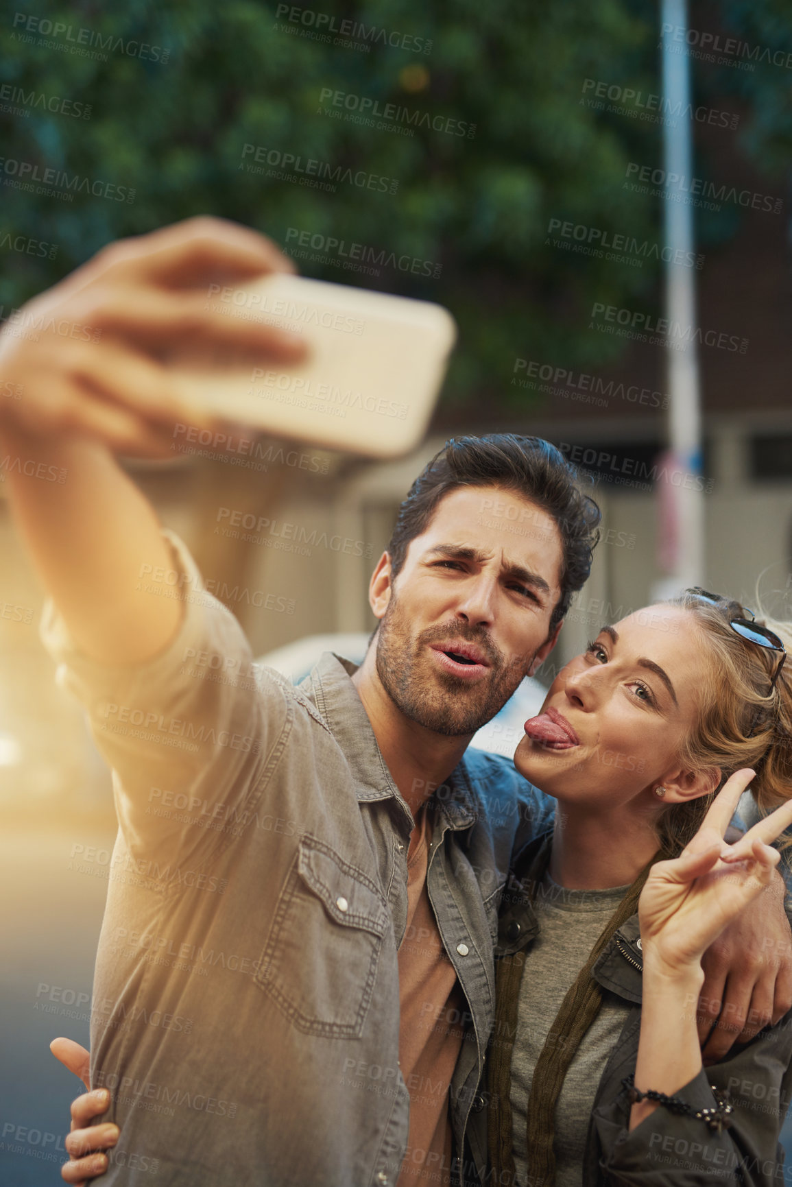 Buy stock photo Couple, selfie and hug with smile in city, tongue and peace sign with care, love and photography. People, man and woman with emoji, profile picture and funny with memory on social network in Berlin