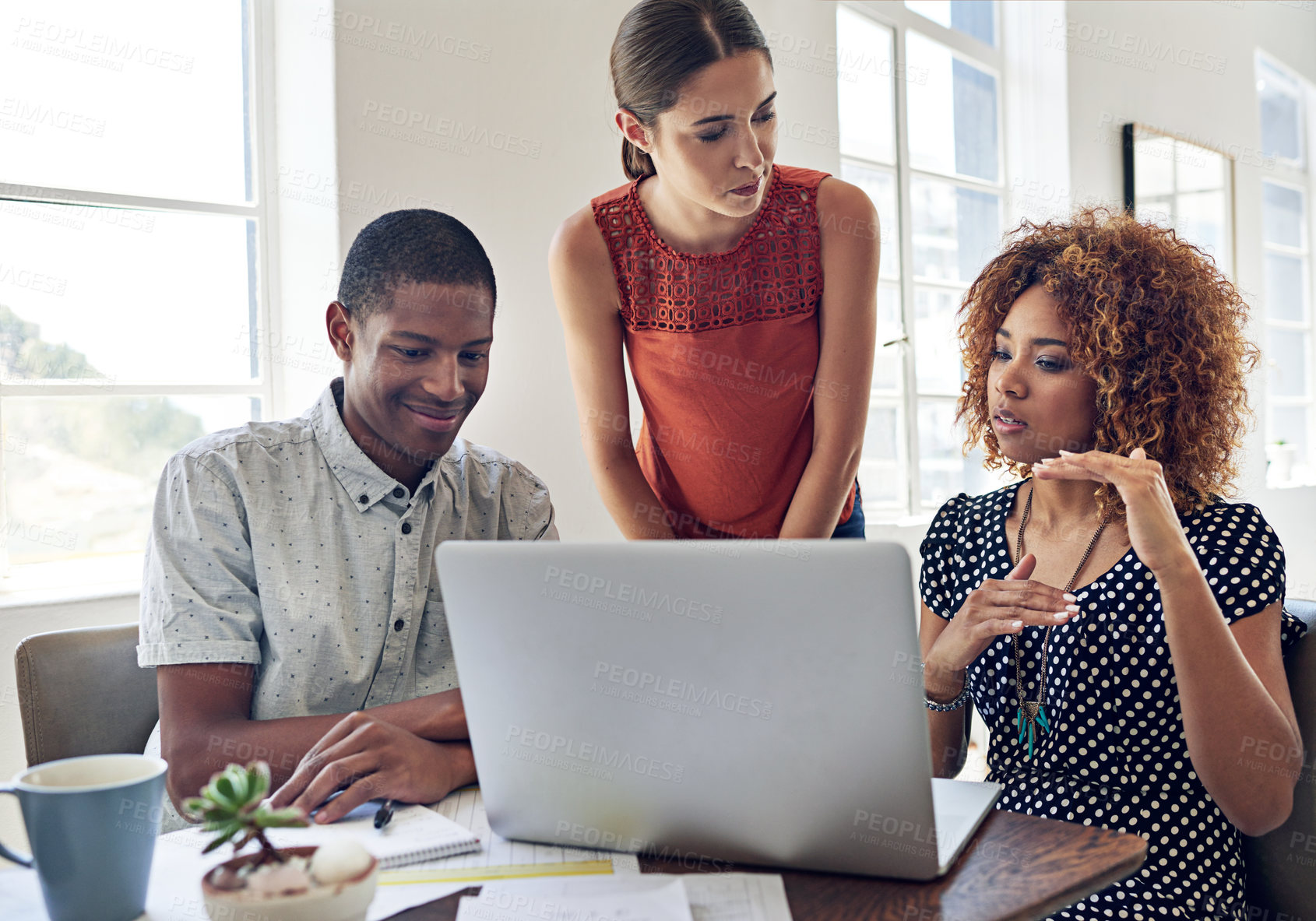 Buy stock photo Shot of a group of colleagues working together on a laptop in an office