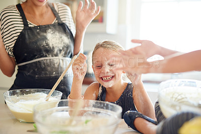 Buy stock photo Shot of two little girls having fun while baking with their mother in the kitchen