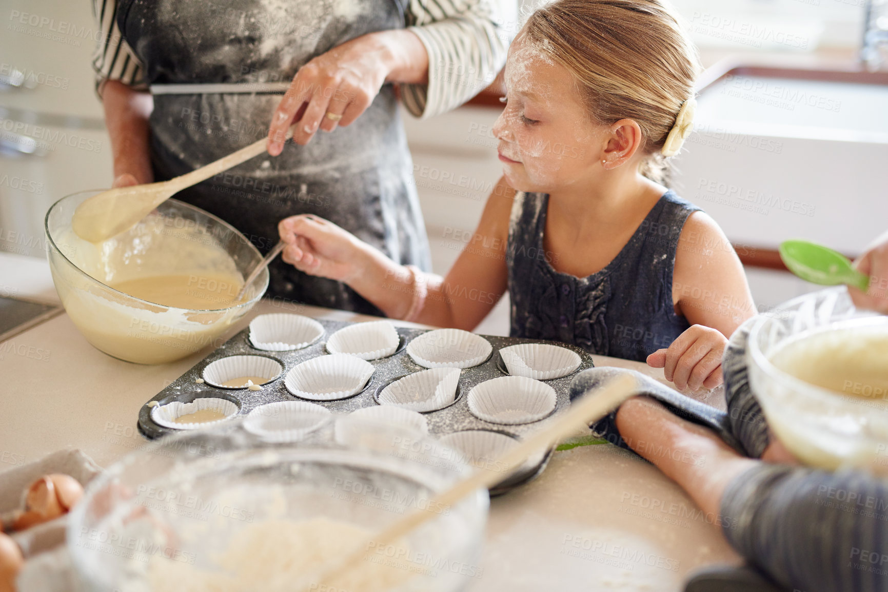 Buy stock photo Shot of two little girls baking with their mother in the kitchen