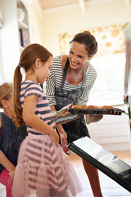 Buy stock photo Shot of two little girls baking with their mother in the kitchen