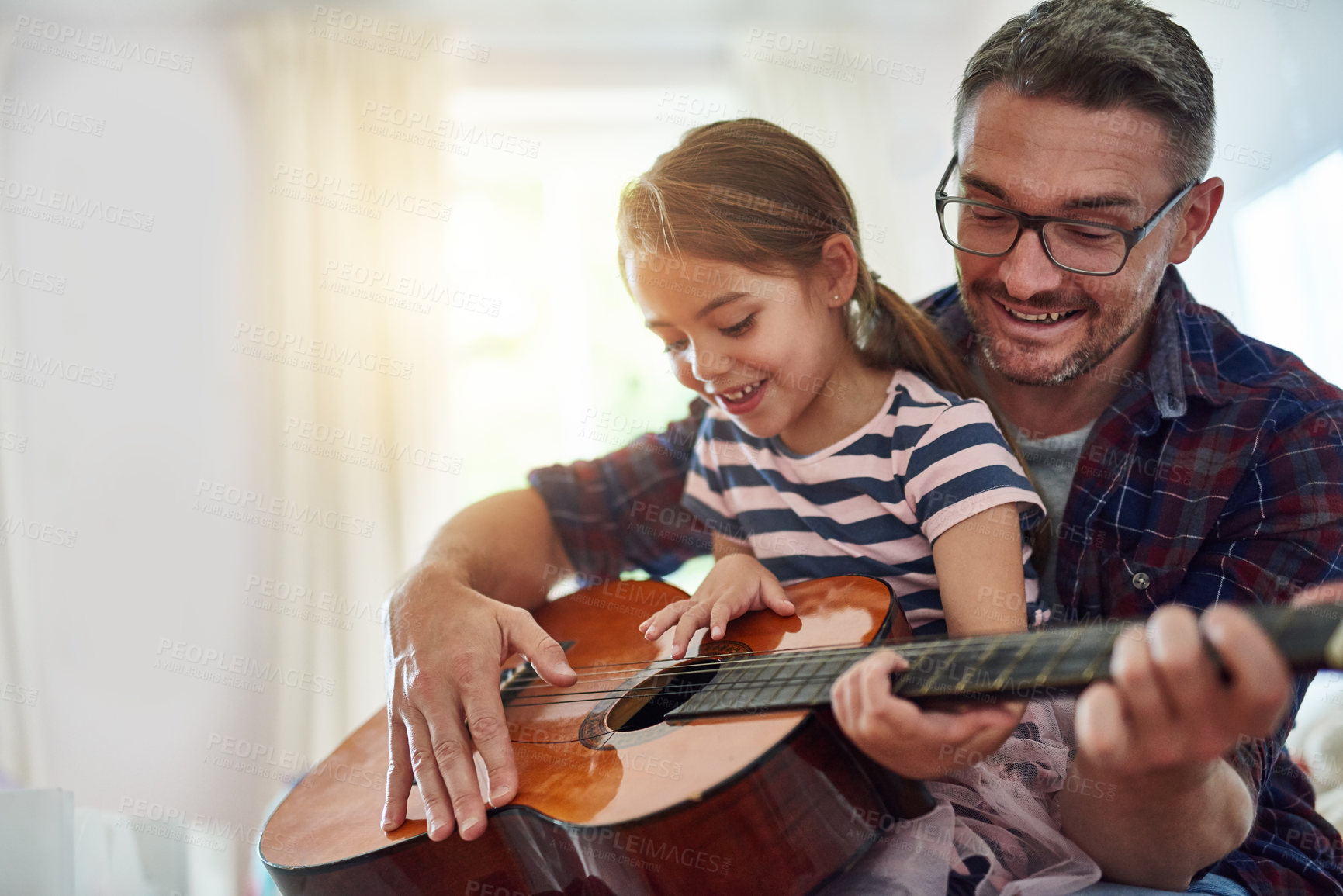 Buy stock photo Father, girl and learning guitar in home, bonding and having fun together. Dad, child and playing acoustic instrument, teaching or education for music lesson, smile and enjoying quality time in house