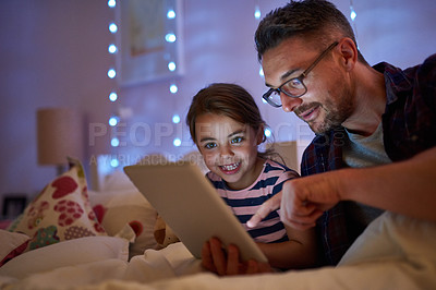 Buy stock photo Shot of a little girl and her father using a tablet before bedtime