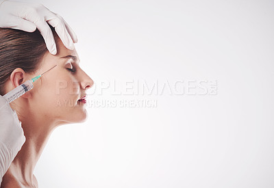 Buy stock photo Studio shot of an attractive young woman getting an injection for cosmetic purposes